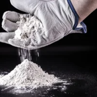 Gloved hand sprinkling white titanium dioxide powder