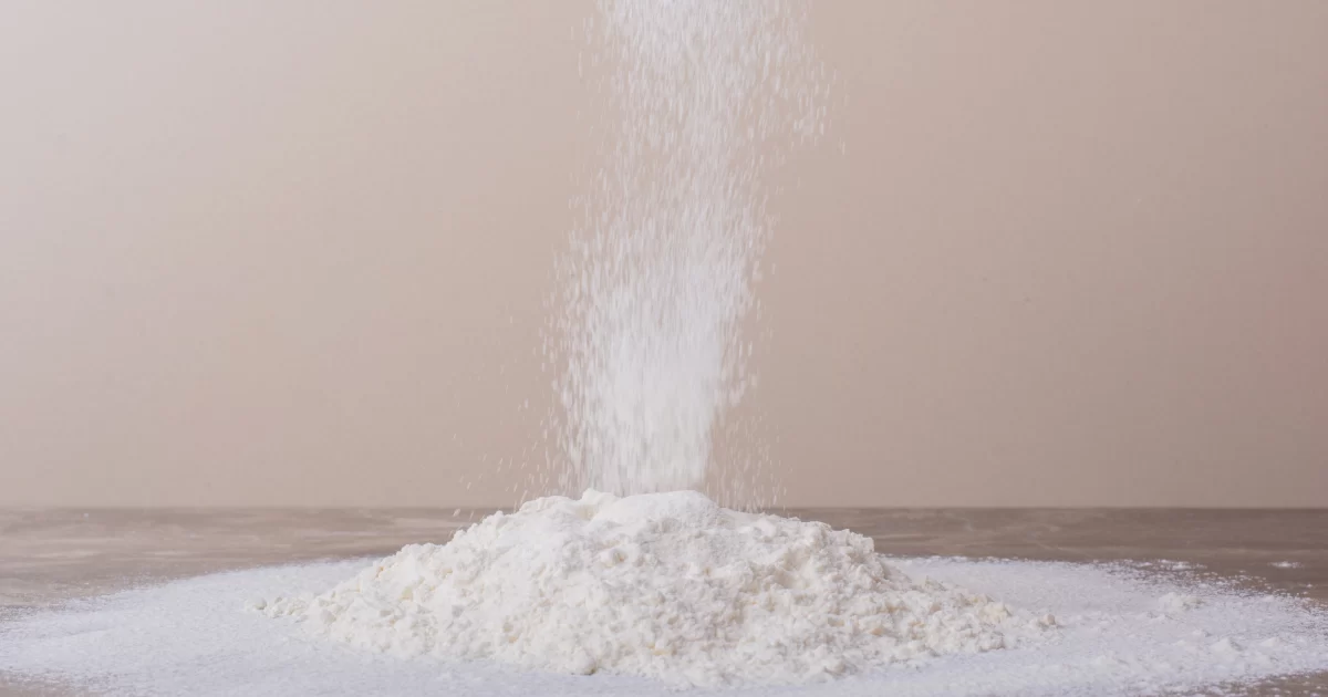 Fine ferric phosphate powder forming a white pile on a wooden surface.