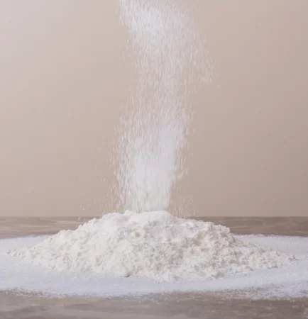 Fine ferric phosphate powder forming a white pile on a wooden surface.