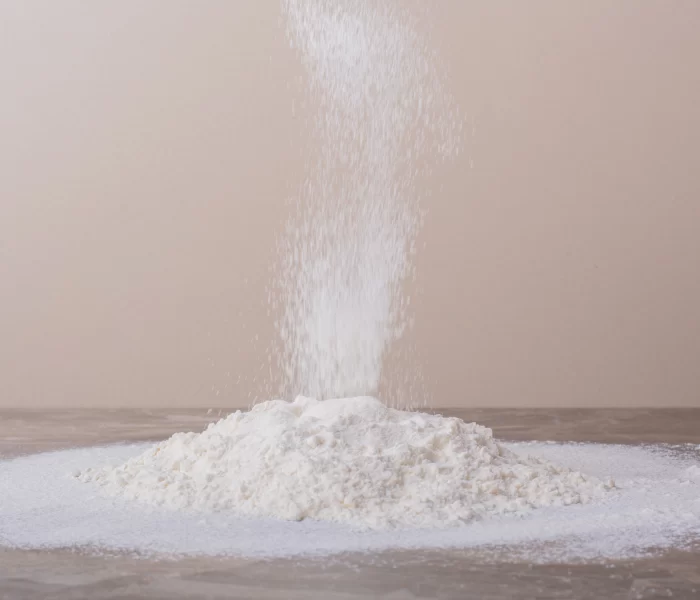 Fine ferric phosphate powder forming a white pile on a wooden surface.