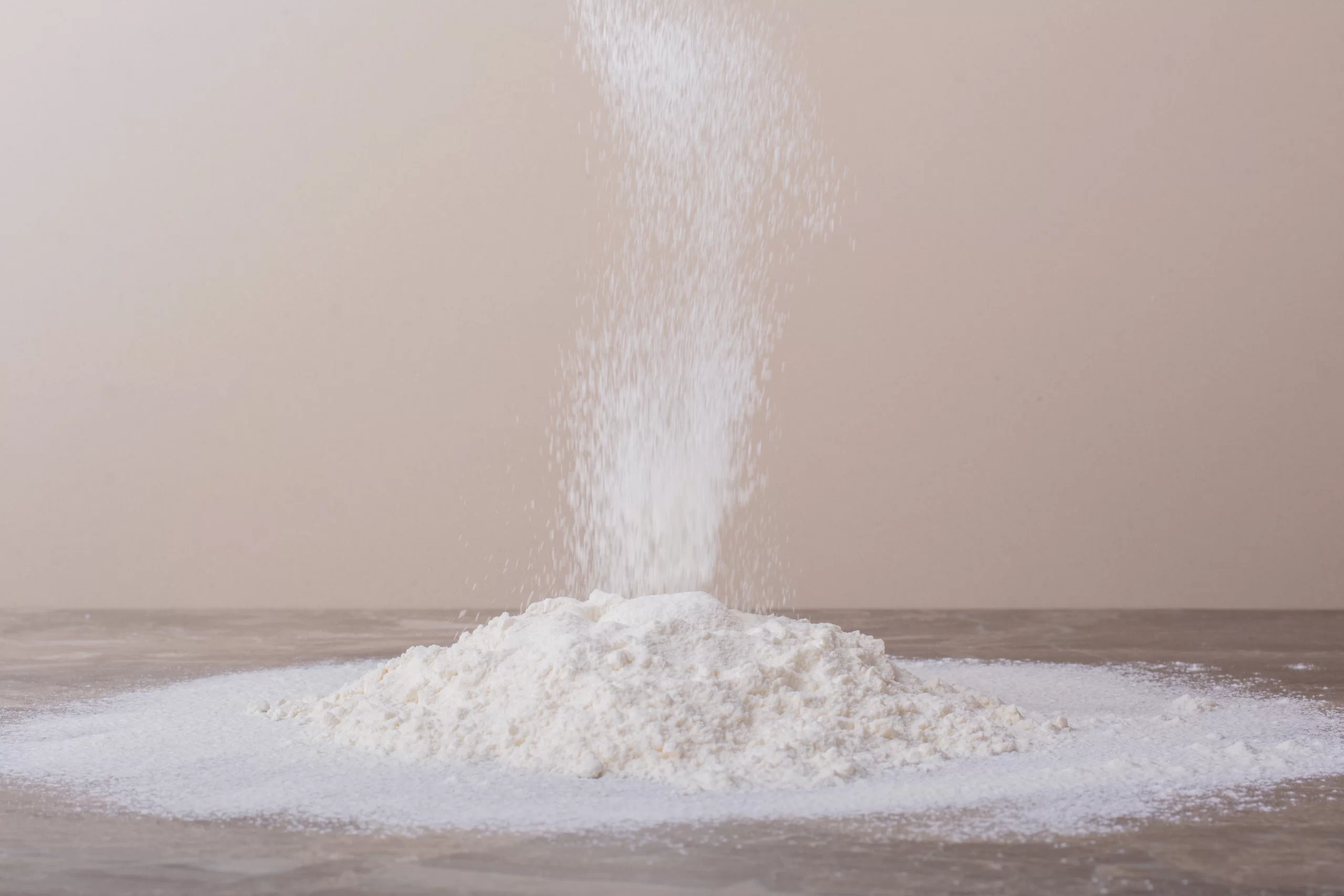Fine ferric phosphate powder forming a white pile on a wooden surface.