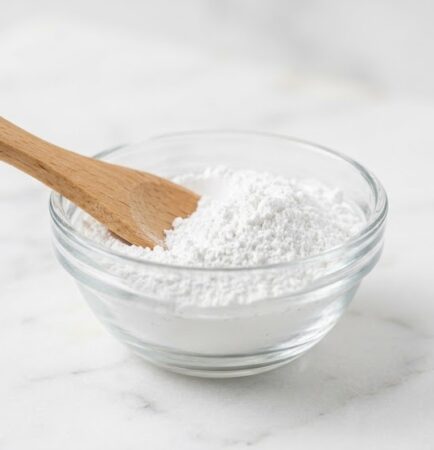 Anhydrous aluminum silicate powder in a glass bowl with wooden spatula