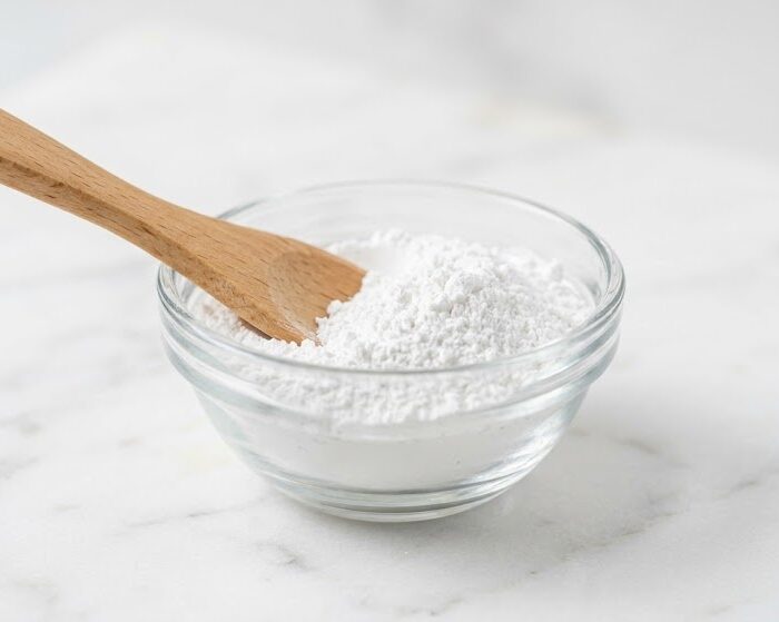 Anhydrous aluminum silicate powder in a glass bowl with wooden spatula